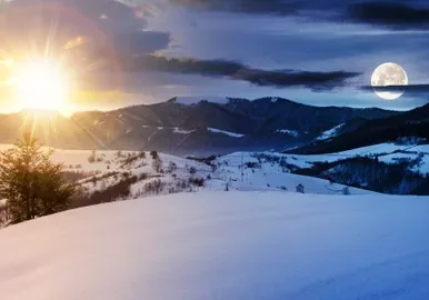 Sunset and moon over snowy landscape